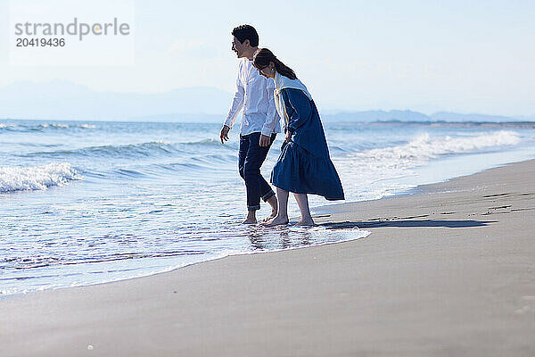 Japanese couple walking on the beach