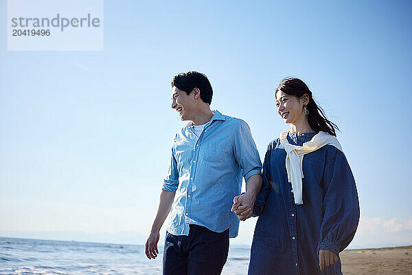 Japanese couple walking on the beach holding hands