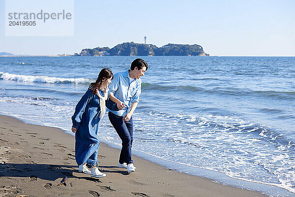 Japanese couple walking on the beach