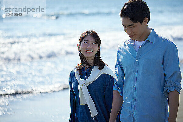 Japanese couple walking along the beach