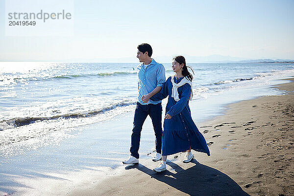 Japanese couple walking on the beach