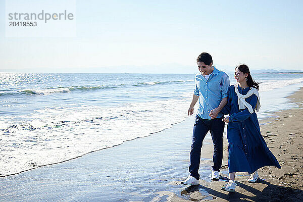 Japanese couple walking on the beach