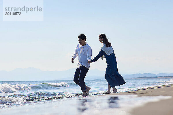 Japanese couple walking on the beach holding hands