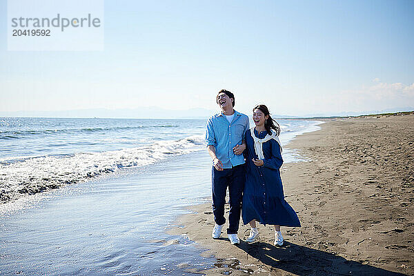 Japanese couple walking on the beach