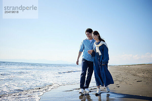 Japanese couple walking on the beach