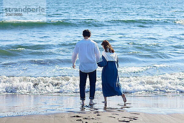 Japanese couple walking on the beach holding hands