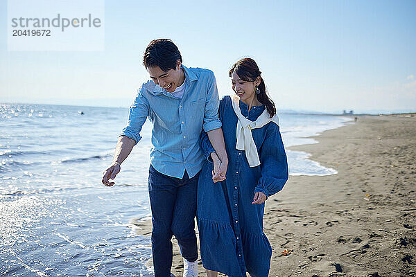 Japanese couple walking on the beach holding hands