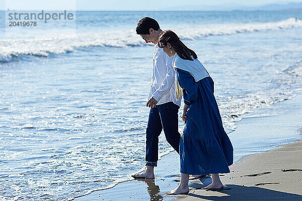 Japanese couple walking on the beach