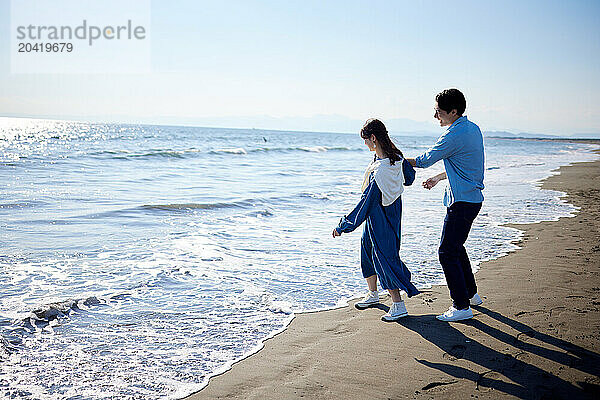 Japanese couple walking on the beach