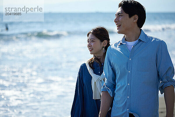 Japanese couple walking on the beach