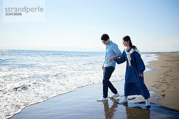 Japanese couple walking on the beach