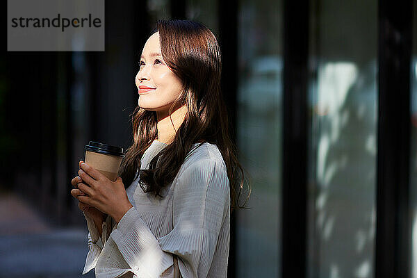 Japanese woman holding coffee cup outdoors