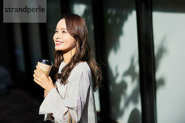 Japanese woman holding a coffee cup and smiling