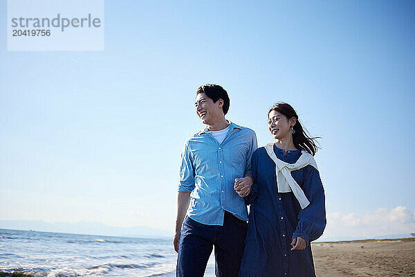 Japanese couple walking on the beach holding hands