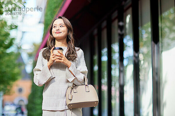 Japanese woman holding coffee and purse in city