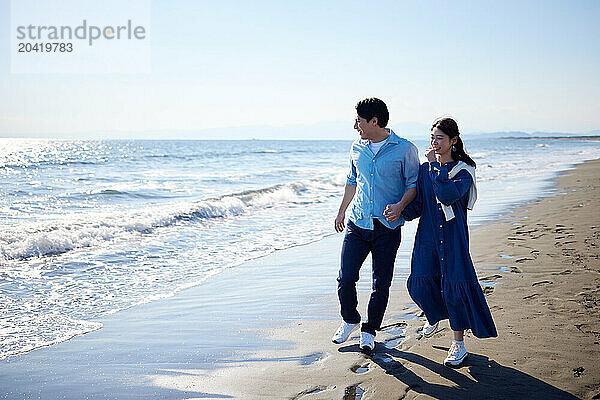 Japanese couple walking on the beach