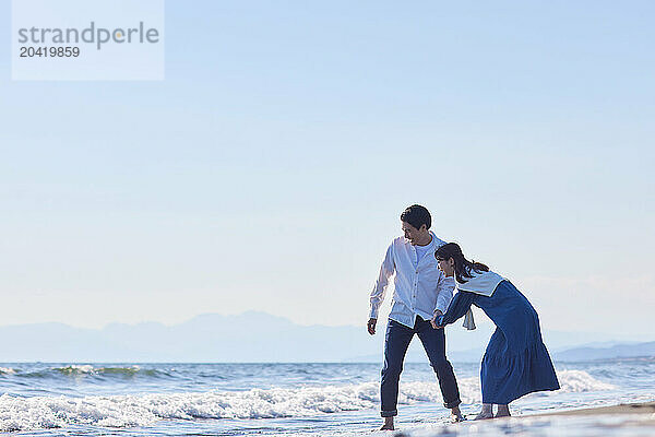 Japanese couple walking on the beach