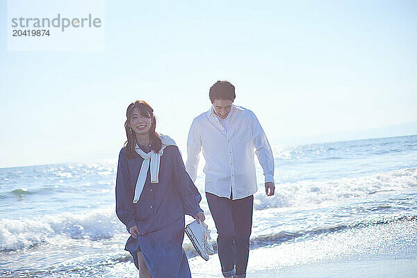 Japanese couple walking on the beach