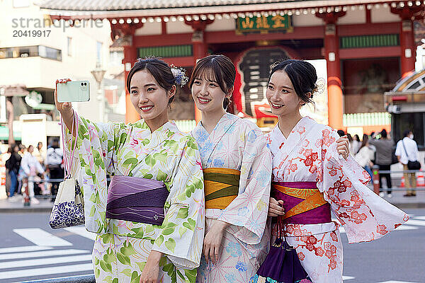 Japanese friends wearing yukata visiting traditional temple in Tokyo