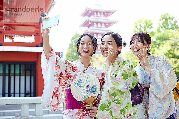 Japanese friends wearing yukata visiting traditional temple in Tokyo