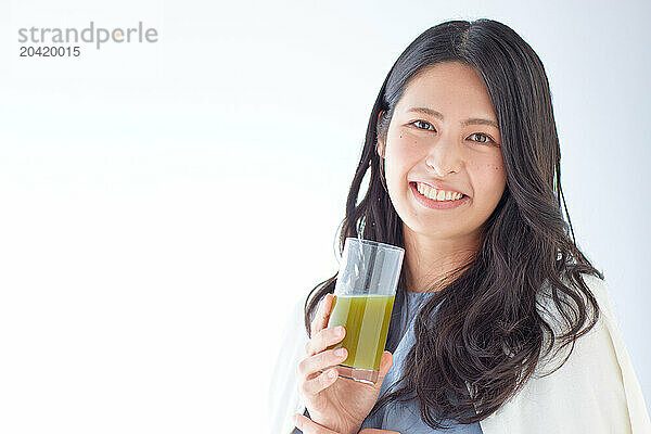 Japanese woman holding a glass of green juice