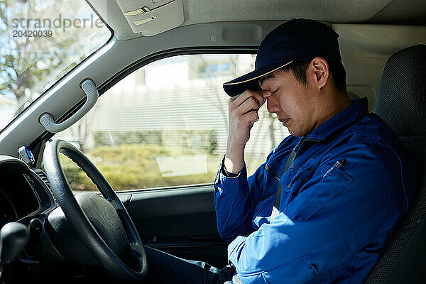 Japanese delivery man sitting in the driver seat