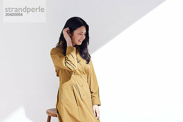 Japanese woman in a brown dress standing in front of a white wall