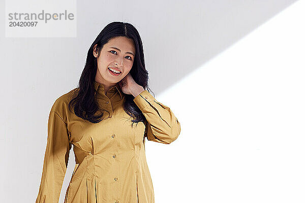 Japanese woman in a brown dress standing in front of a white wall