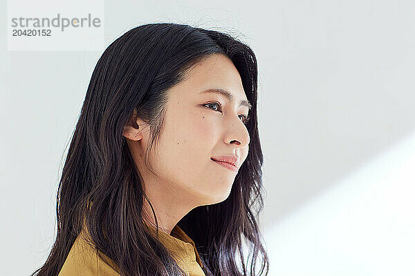 Japanese woman in a brown dress standing in front of a white wall