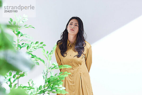 Japanese woman in a brown dress standing in front of plants