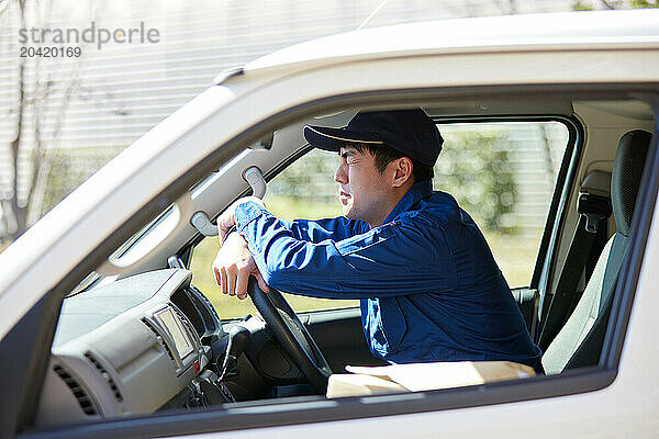 Japanese delivery man sitting in the driver seat