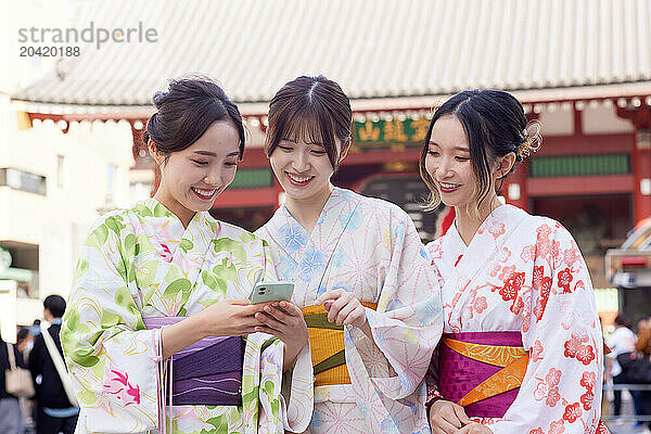 Japanese friends wearing yukata visiting traditional temple in Tokyo