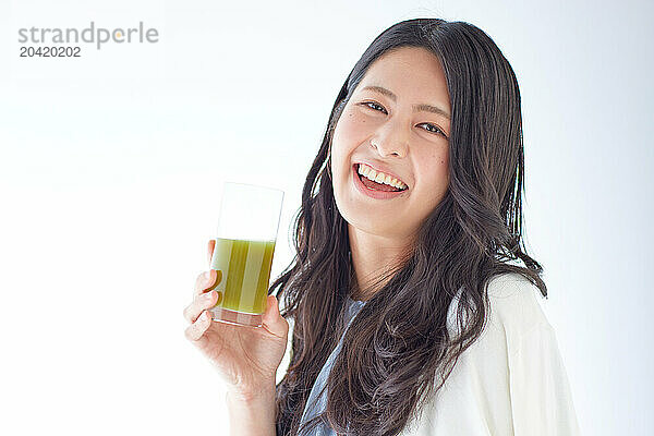 Japanese woman holding a glass of green juice