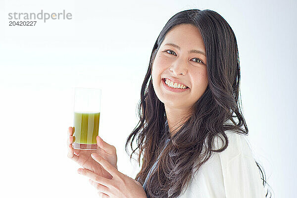 Japanese woman holding a glass of green juice