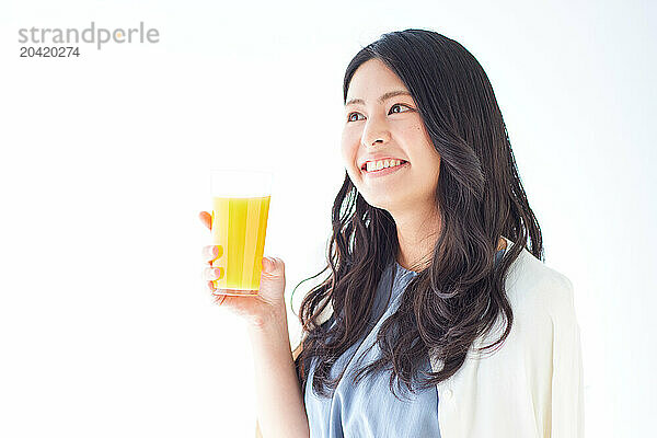 Japanese woman holding a glass of orange juice