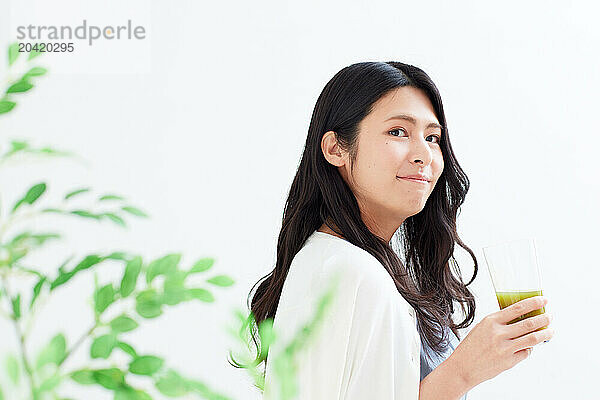 Japanese woman holding a glass of green juice