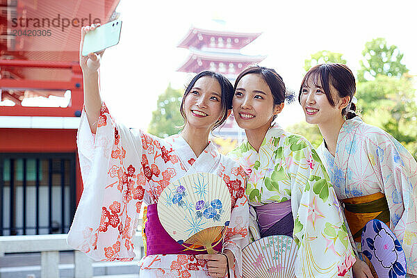 Japanese friends wearing yukata visiting traditional temple in Tokyo