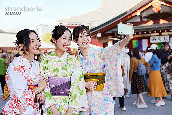 Japanese friends wearing yukata visiting traditional temple in Tokyo