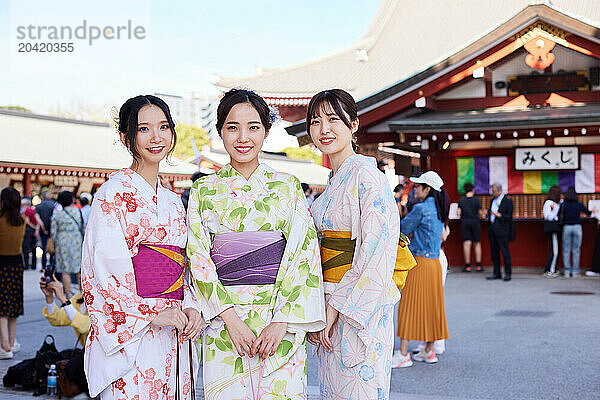 Japanese friends wearing yukata visiting traditional temple in Tokyo