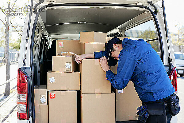 Japanese delivery man checking boxes in the car