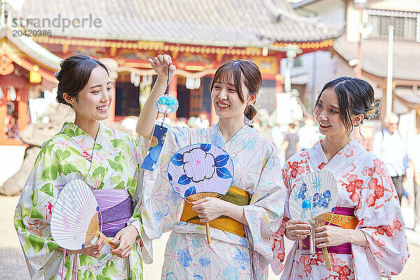 Japanese friends wearing yukata visiting traditional temple in Tokyo