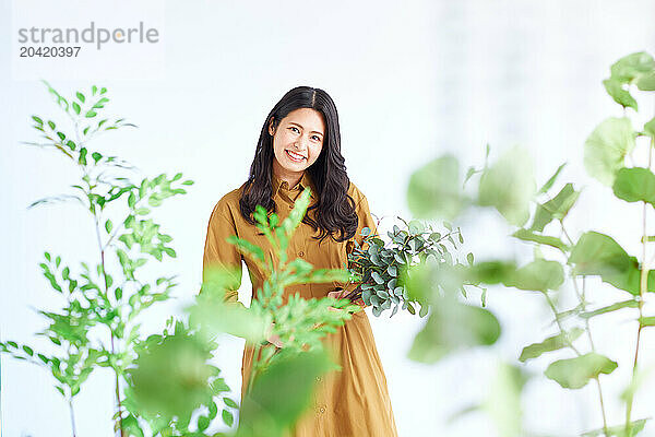 Japanese woman in a brown dress standing in front of plants