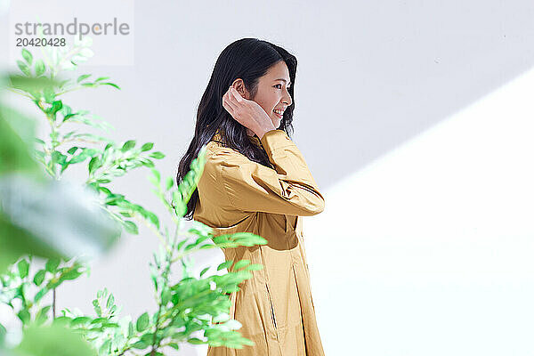 Japanese woman in a brown dress standing in front of plants