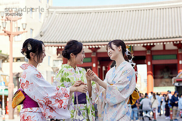 Japanese friends wearing yukata visiting traditional temple in Tokyo