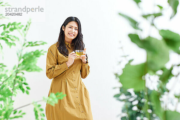 Japanese woman in a brown dress standing in front of plants