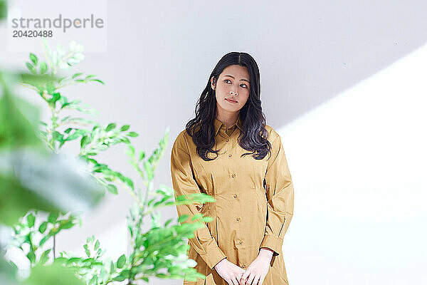 Japanese woman in a brown dress standing in front of plants