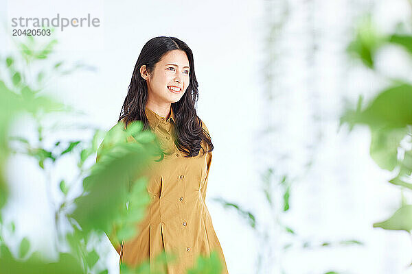 Japanese woman in a brown dress standing in front of plants