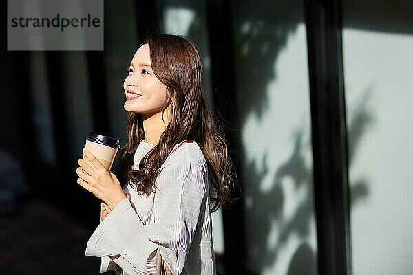 Japanese woman holding coffee cup and smiling