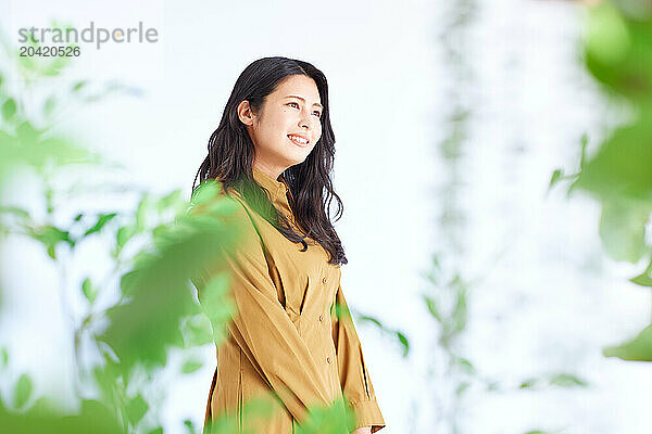 Japanese woman in a brown dress standing in front of plants