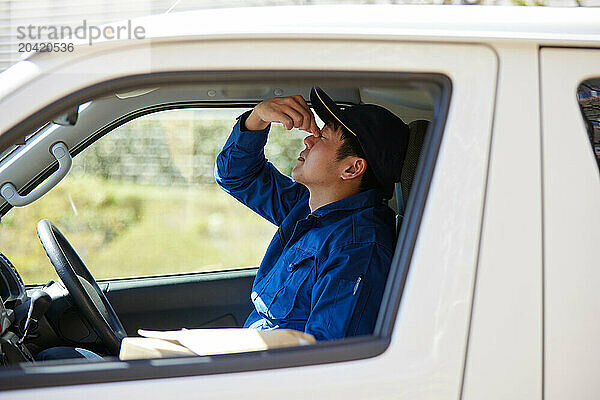 Japanese delivery man sitting in the driver seat